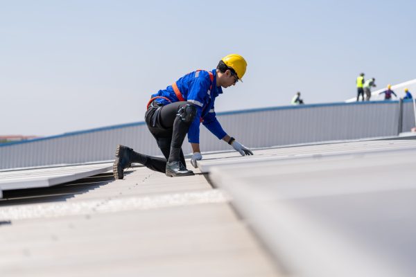 Specialist technician professional engineer checking top view of installing solar roof panel on the factory rooftop under sunlight. Engineers having service job of electrical renewable eco energy